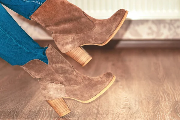 close-up. Women\'s suede boots. Women\'s brown shoes. Warm boots are put on legs at the girl. Shoe fitting.Concept of buying, trying on shoes and boots.