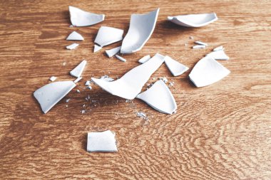 Arka planda kırık bir tabağın beyaz parçaları var. Parçalanmış bir tabağın kıymıkları. Yerde beyaz bir sofra takımının parçaları vardı. Kırık bir tabağın parçaları.