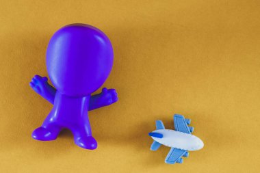 Uçak, uçak. İnsan figürü. Sarı arka planda bir adam ve bir uçak figürü. Seyahat konsepti. Hava yolculuğu kavramı