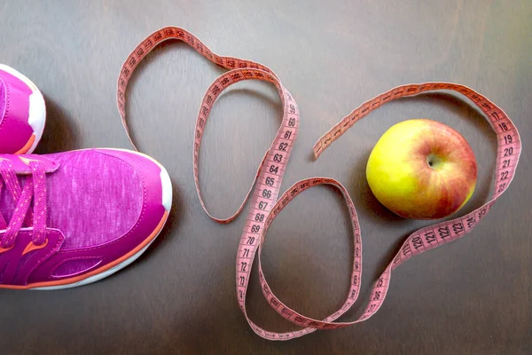 Close up apple, meter tape, pink sneakers. Concept Healthy way of life. top view. The first step to a diet and a healthy way of life.