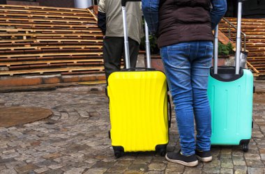 İki renkli bavulu olan kişi. Yolculuk için bavullar. Renkli çantalar. Konsept hareket, seyahat, seyahat, uçuş. Yaz tatili kavramı, tatiller. seyahat için bavul.