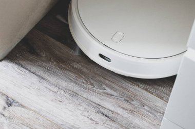 Beyaz robot elektrikli süpürge. Robot yorucu enerjiyi şarj ediyor. Üst Manzara. Daire Temizleme Yardımcı Robot Konsepti