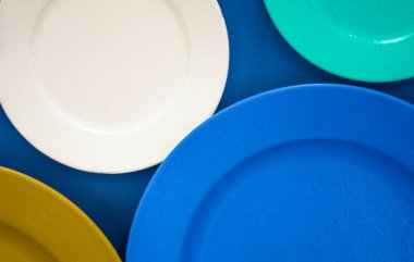 Farklı renklerde tabaklar. Arka planda farklı boyutlarda renkli ziller ayarlayın. sofra takımlarının ve eşyaların çeşitliliği. Farklı boyutlarda, renkli boş tabaklar. Yumuşak bulanıklık.