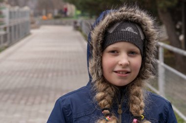  Kalın ceketli bir genç. Saçları örgülü, şapkalı, sıcacık giyinmiş bir kız. Güzel bir kızın portresi Sonbahar sonu, ilkbahar başı