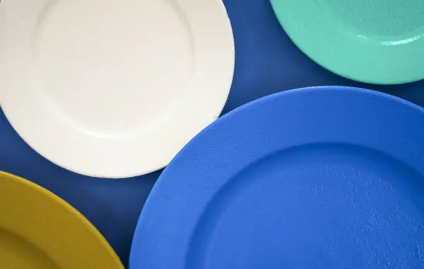 plates of different colors. set colorful cymbals  of different sizes on  background. diversity of tableware and ware. Different sizes, color empty plates. Soft blur.