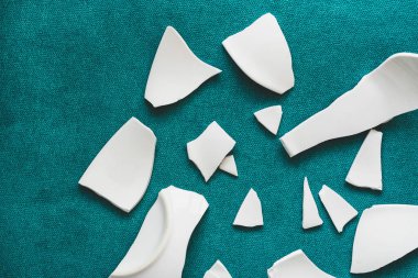 Kırık beyaz kapların kıymıkları ve parçaları. Bir aile kavgasının metaforu. Kırık tabak, cam. Mutfaktaki kaza kavramı. Parçalanmış tabak parçaları.. 