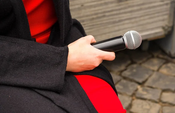 female hand holding microphone. Reporter interviewing outdoors. The concept to speak, record with the microphone, to interview, the press, TV