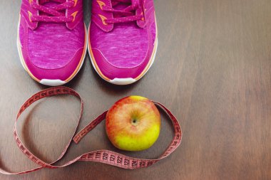 Elma, metre bandı, pembe spor ayakkabılar. Sağlıklı yaşam biçimi kavramı. Üst Manzara. Rejimin ilk adımı ve sağlıklı bir yaşam tarzı..