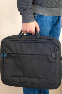 Yakın plan. Elinde çanta, elinde dizüstü bilgisayar çantası, bilgisayar taşıma konsepti, dizüstü bilgisayar koruyucu klasörü. yan görünüm