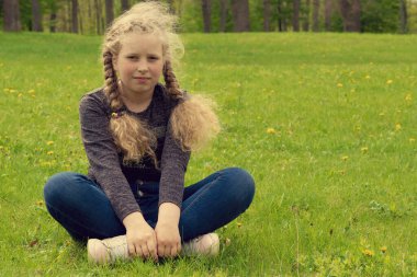 Komik kız. Çocuk yeşil çimlerin üzerinde yatıyor. Piknikteki mutlu çocuk. Bahar, yaz konsepti. çocukluk kavramı