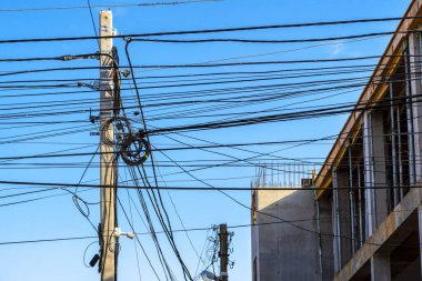 Kablolu direk. Elektrik direklerindeki kablolar. Beton bir sütunda fiber optik kablo kayışı. Telekomünikasyon ve internet. Karışık elektrik kabloları