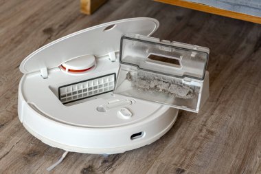Beyaz robot elektrikli süpürge. Çöp konteyneri. Yakın plan. Arkaplanda robot süpürgesi var.