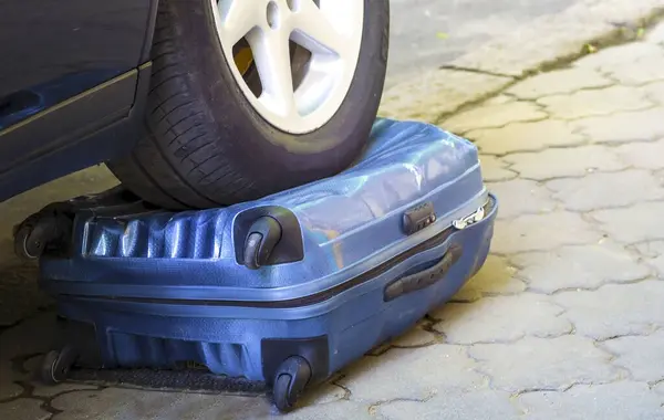 Car wheel on the suitcase. The destroyed baggage. Concept of a reliable suitcase for luggage and travel. Spoiled baggage. The car ran over an item. obstacles on the road