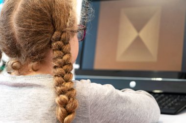 Gözlüklü kız. Bilgisayarın başında bir kız var. Çocuklarda vizyon tedavisi kavramı. Görüntüyü iyileştirmek için monitördeki programlar.