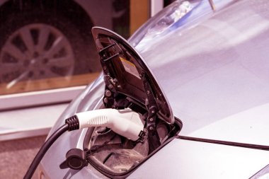 Elektrikli bir arabaya takılı güç kaynağını kapatın. Elektrikli bir arabanın güç prizinin görüntüsünü kapatın, şarj oluyor. Çevre dostu alternatif enerji kavramı