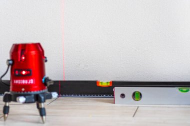 Lazer seviyesi ve kabarcık seviyeleri, duvardaki çizgiler. Kırmızı lazer seviyesiyle ölçümleme. Ölçüm doğruluğu konsepti, modern ölçüm cihazları