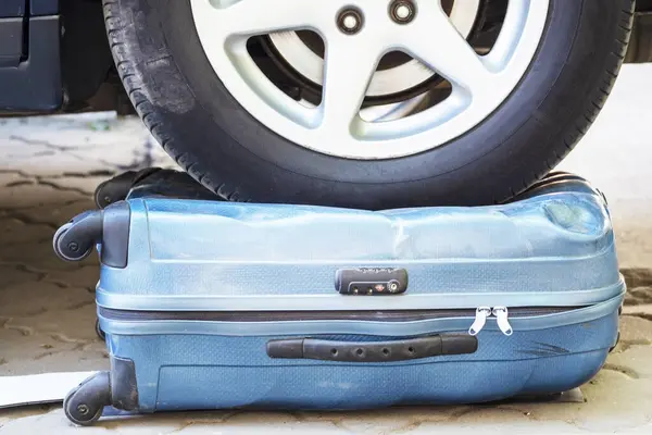 Car wheel on the suitcase. The destroyed baggage. Concept of a reliable suitcase for luggage and travel. Spoiled baggage. The car ran over an item. obstacles on the road
