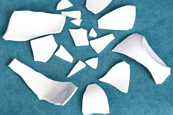 Splinters and Fragments of the broken white ware. Metaphor of a family quarrel. Broken Plate, glass. The concept of accidents in the kitchen. Pieces of shattered dishes.