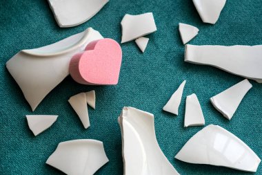 Parçaların arasında bir kalp. Mutsuz aşkın sembolü. Kötü sağlık konsepti. Beyaz parçalar ve kalp. yan görünüm