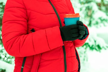 Kollar kahve ve kağıt bardak tutuyor. Karlı arka planda tek kullanımlık bir bardak tutan eller. Kış konseptine uygun kahve. Sıcak ve sıcak içecekler kış konseptinde.