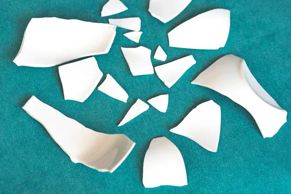 Kırık beyaz kapların kıymıkları ve parçaları. Bir aile kavgasının metaforu. Kırık tabak, cam. Mutfaktaki kaza kavramı. Parçalanmış tabak parçaları.. 