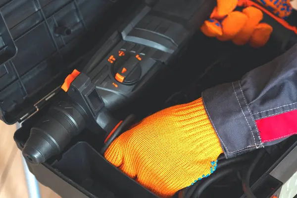  Koruyucu eldivenli eller, yakın plan çekiç. İşçi çekiç delgisini kutudan çıkarır..