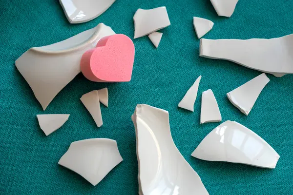 Parçaların arasında bir kalp. Mutsuz aşkın sembolü. Kötü sağlık konsepti. Beyaz parçalar ve kalp. yan görünüm