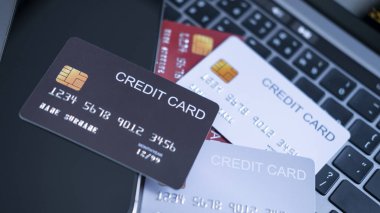 Farklı renklerde kredi kartı koleksiyonu, akıllı telefonun yanındaki dizüstü bilgisayarın klavyesinde. Finansal işlemlerde çoklu ödeme seçenekleri, dijital bankacılık ve güvenli çevrimiçi işlemler kavramı.