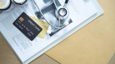 Steteskop ve tıbbi formların yanına yerleştirilen altın kredi kartı hastane giderlerini vurguluyor.