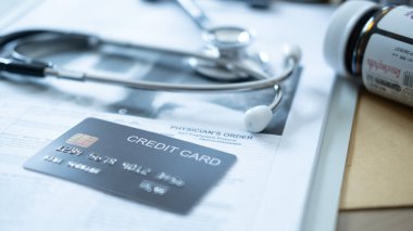 Sağlık kredisi ödemesini temsil eden steteskop ve ilaç şişesiyle tıbbi belgelerde siyah kredi kartı..