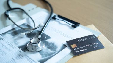 Tıbbi maliyet yönetimi ve ödemeleri temsil eden tıbbi raporlara steteskop ile siyah bir kredi kartı konmuş.