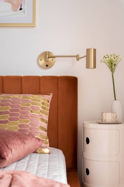 Modern masanın yanında şık dekorasyonlar, kadife yatak başlığı ve güzel yastıklarla rahat ve zarif bir yatak.