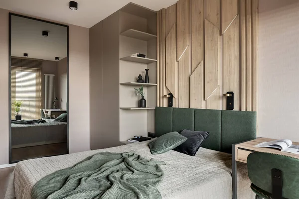Cozy bedroom with mirror, wooden wall behind bed with green headboard