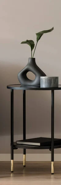 Vertical panorama of stylish vase and decorative box on modern, black side table with golden details