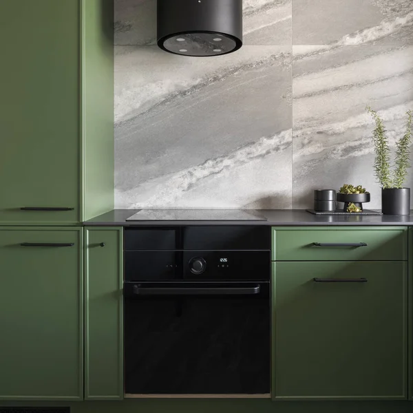 Modern black oven, kitchen hood and countertop in trendy kitchen with green cupboards
