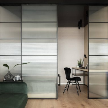 Simple home office space with desk and black chair in living room with tempered glass wall and sliding doors