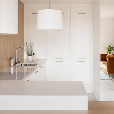 Small and stylish kitchen with aesthetic white furniture, lamp, kitchen hood and wooden wall