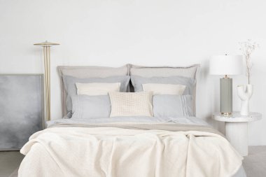 Elegant and bright bedroom with big bed with blue and white bedclothes and stylish decorations