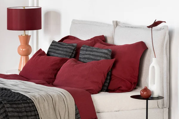 舒适的床 床上用品有红黑相间的床上用品和枕头 米色的床头板和床头柜上的装饰品 — 图库照片