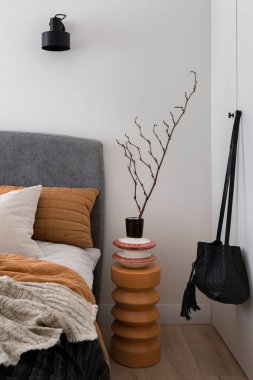 Eşsiz, koyu turuncu, şık dekorasyonları olan komodinli yatak odasındaki beyaz gardırop.