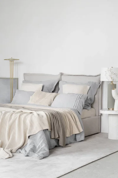 舒适的床 明亮宽敞的卧室里有蓝色 灰色和米黄色的床上用品和枕头 — 图库照片