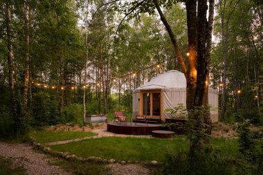 Yeşil ormandaki büyüleyici süslemeleriyle glamping tarzı tatil için güzel bir yurt çadırı