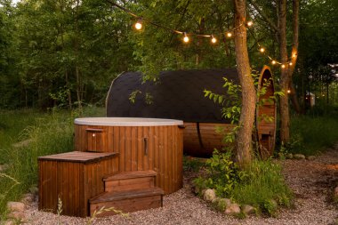 Hot tub and sauna in glamping camp set in forest clipart