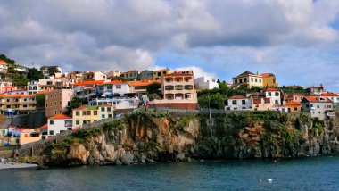 Renkli Akdeniz evleri olan kayalık kıyı kasabası seyahat, mimari, yaşam tarzı ve doğa temalı içerikteki görseller için sakin su anlaşmasının üzerine tünemiştir..