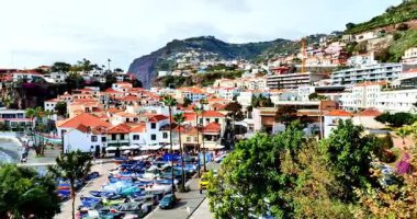 Funchal, Madeira 3 Ağustos 2025: Portekiz 'in başkenti Funchal' da güneşli bir günde renkli evler, park edilmiş arabalar, palmiye ağaçları, turistler, restoranlar ve taksi taksileriyle dolu şehir merkezi.
