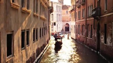 Venedik kanalı altın gibi sıcacık bir ışıkla yıkandı. Gondolunu, Venedik 'in romantizm ve ebedi cazibesini yakalamak için tarihi binalar arasında zarafetle ileri doğru yönlendiren bir gondolcu..