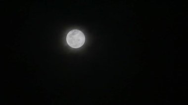 Çiçek ayı kara gece bulutunda parlıyor ve bulutlar geçiyor.