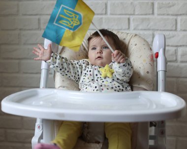 A little girl holds the flag of Ukraine in her hands. Young patriot, blue and yellow flag. A free Ukrainian woman
