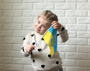 A little girl holds the flag of Ukraine in her hands. Young patriot, blue and yellow flag. A free Ukrainian woman