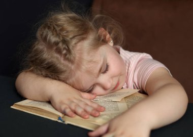 A small child was reading a book and fell asleep on it. Distance Learning